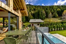 Chalet les Côtés du Lavancher a un balcon avec mobilier de salle à manger donnant sur le grand jacuzzi.